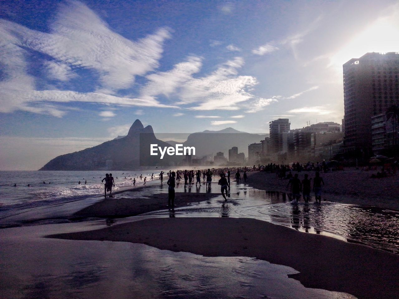 People on beach in city against sky