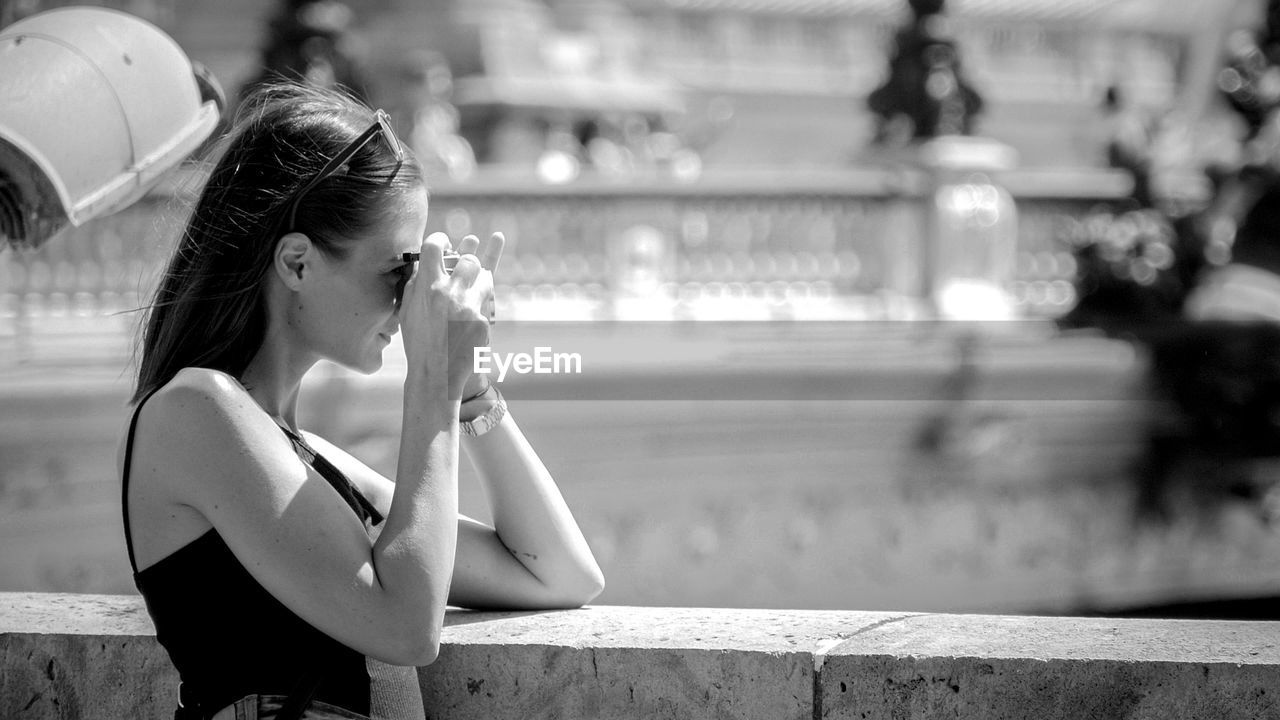 Woman photographing while standing in city