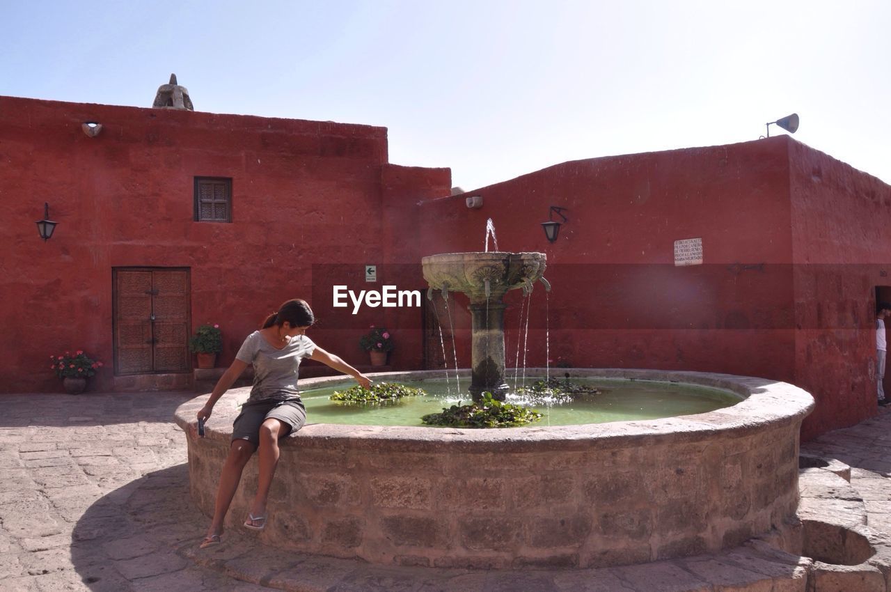 Woman sitting at water fountain