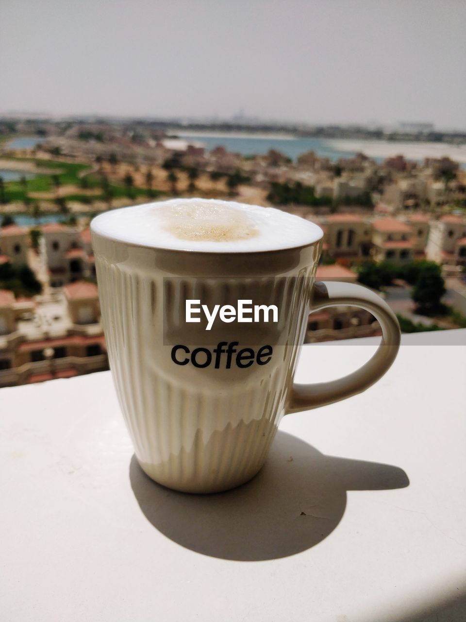 CLOSE-UP OF COFFEE CUP ON TABLE AGAINST CLEAR SKY