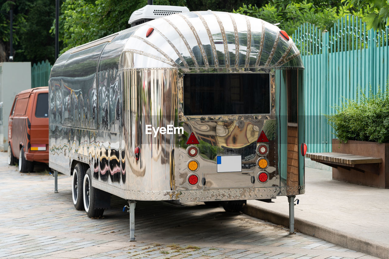 Retro style futuristic silver metal trailer van standing on summer day for fair, festival or event.