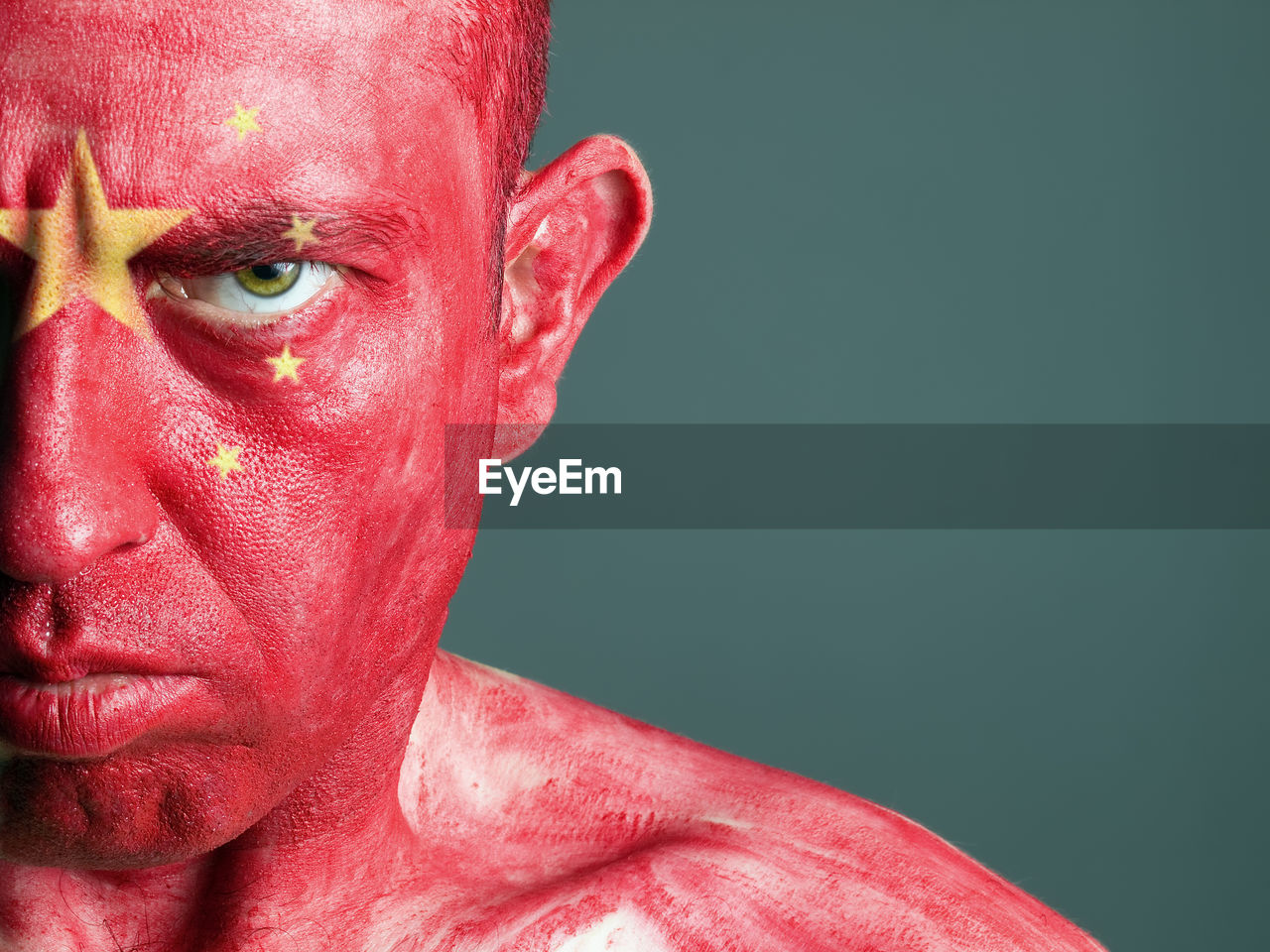 Close-up portrait of man with chinese flag body paint against gray background