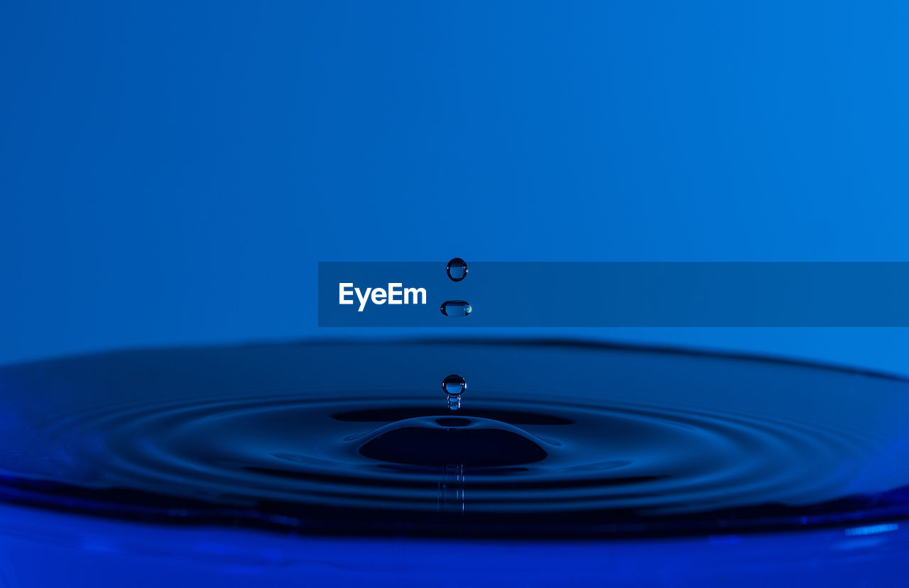 CLOSE-UP OF WATER DROP ON BLUE BACKGROUND