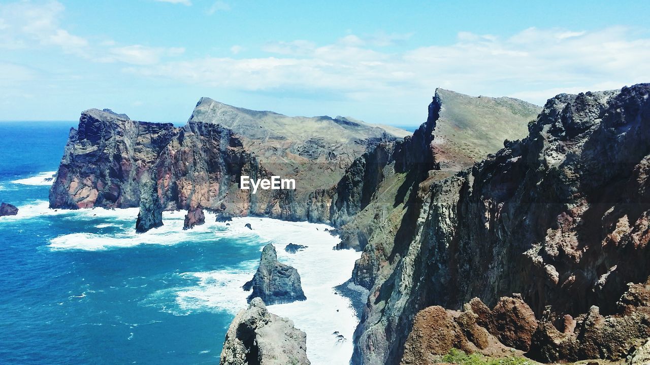 Scenic view of cliffs by sea against sky