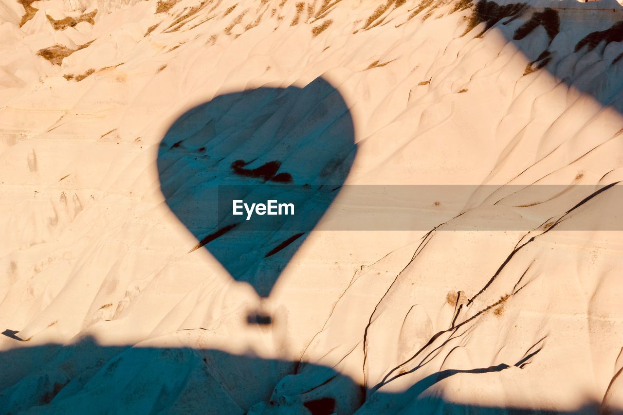 Shadow of hot air balloon on sand during sunny day