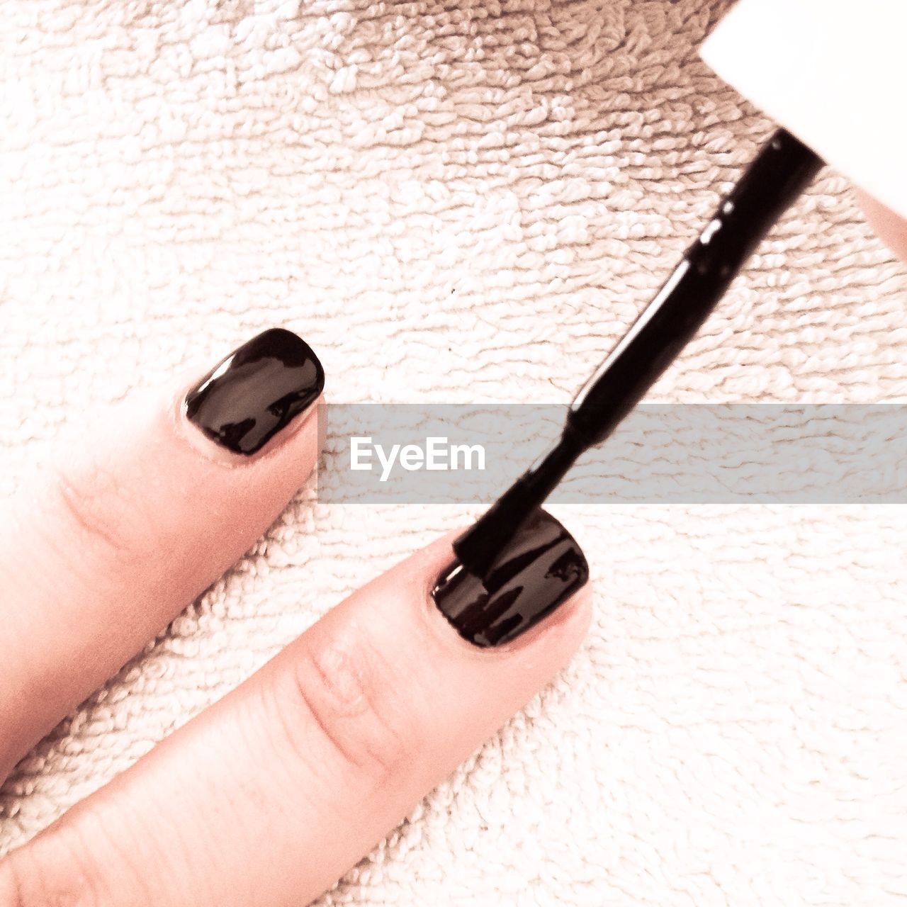 Cropped image of woman applying black nail polish