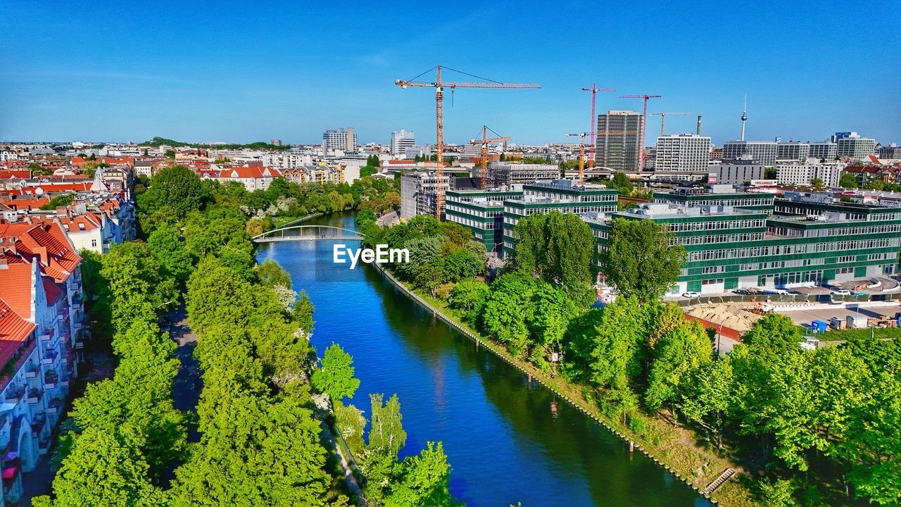 architecture, cityscape, built structure, city, building exterior, water, nature, sky, building, aerial photography, town, blue, plant, urban area, landscape, travel destinations, residential district, skyline, high angle view, business finance and industry, waterway, river, travel, tree, outdoors, no people, transportation, environment, day, clear sky, flower, industry, sunny, nautical vessel, landmark, tourism, urban skyline, business, construction industry, reflection, sunlight, city life