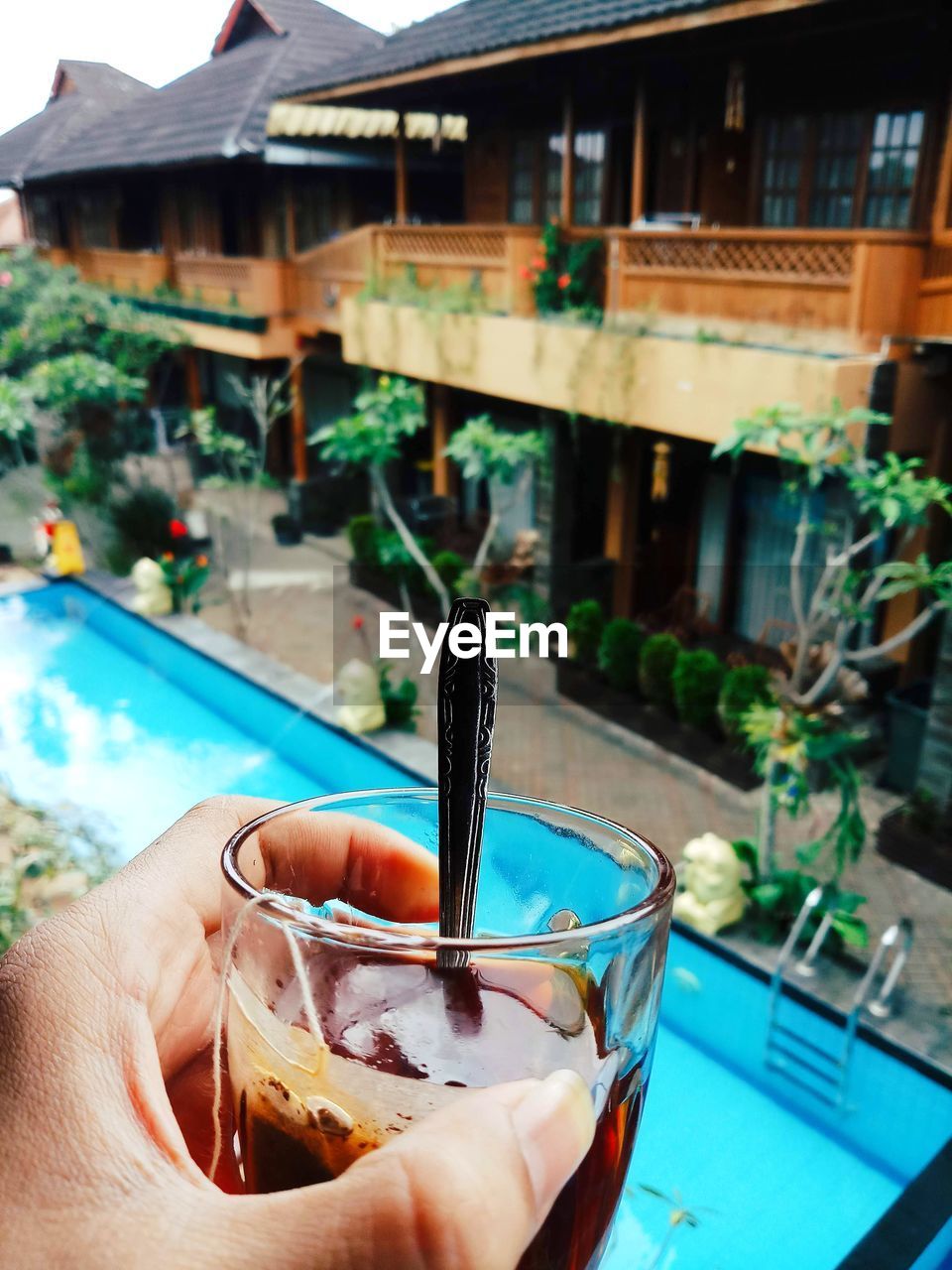 MIDSECTION OF PERSON HOLDING ICE CREAM IN SWIMMING POOL