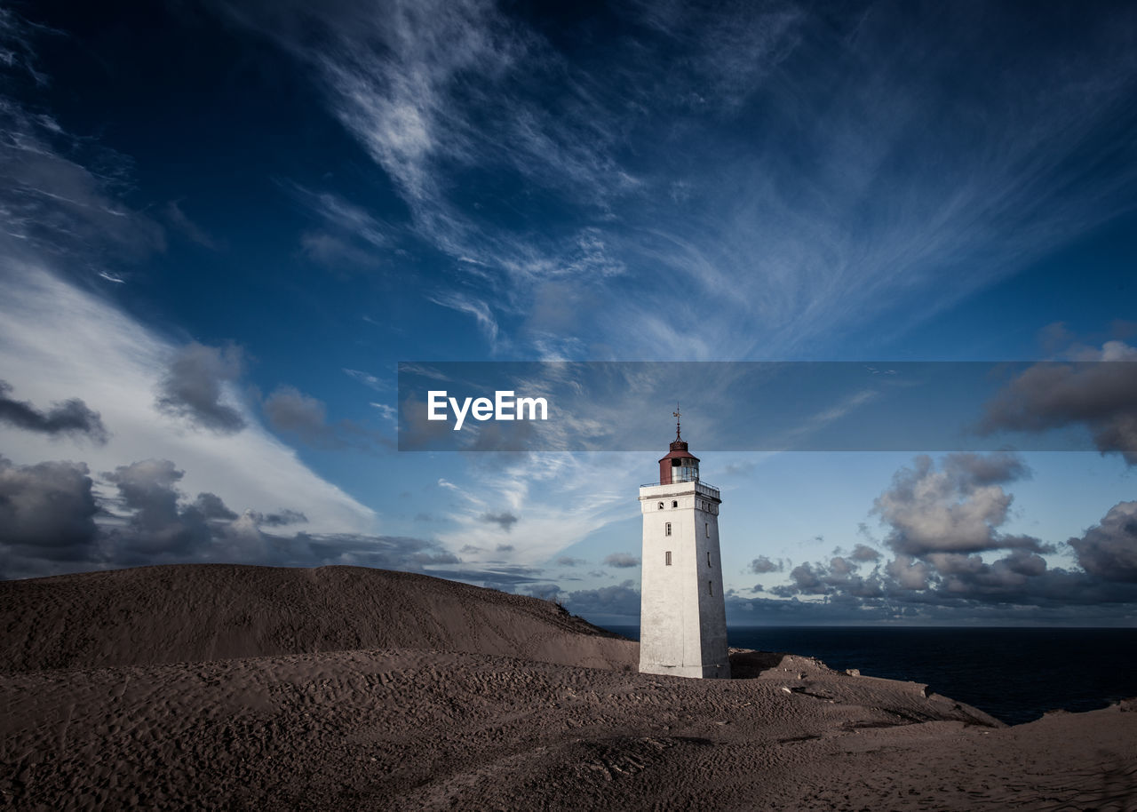 Lighthouse in sand dunes with dramatic sky