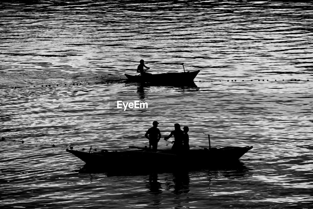 Silhouette people on boat in sea