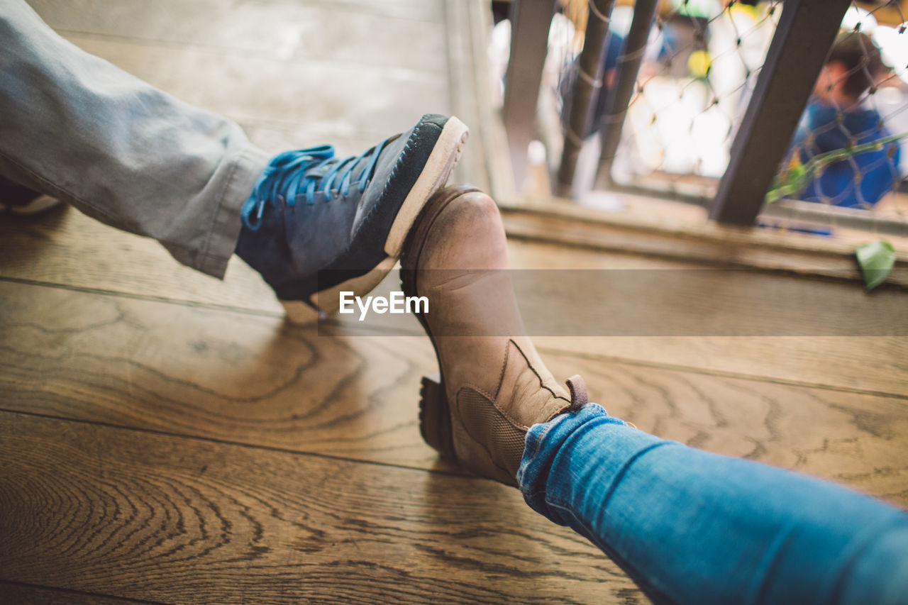 Low section of people wearing shoes on wooden floor