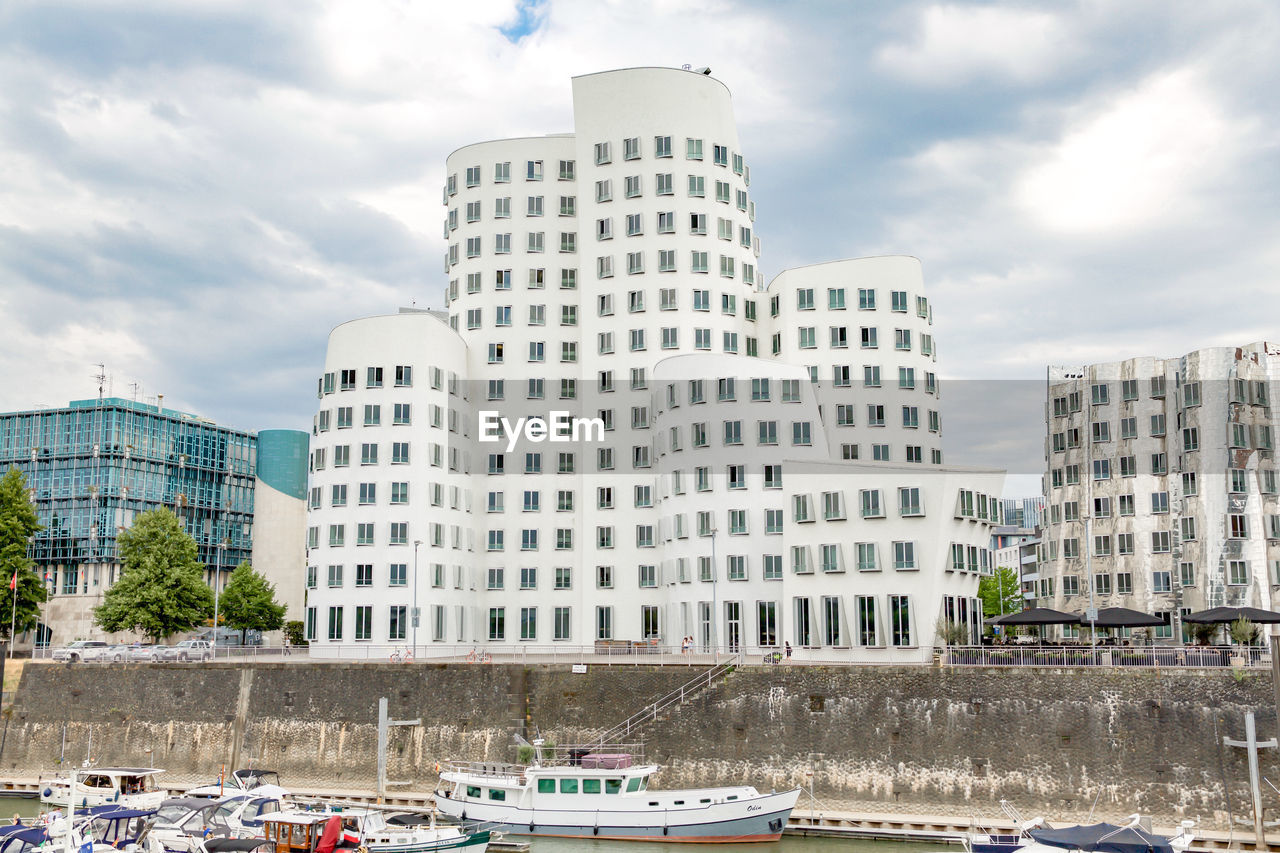 SKYSCRAPERS BY RIVER AGAINST BUILDINGS IN CITY