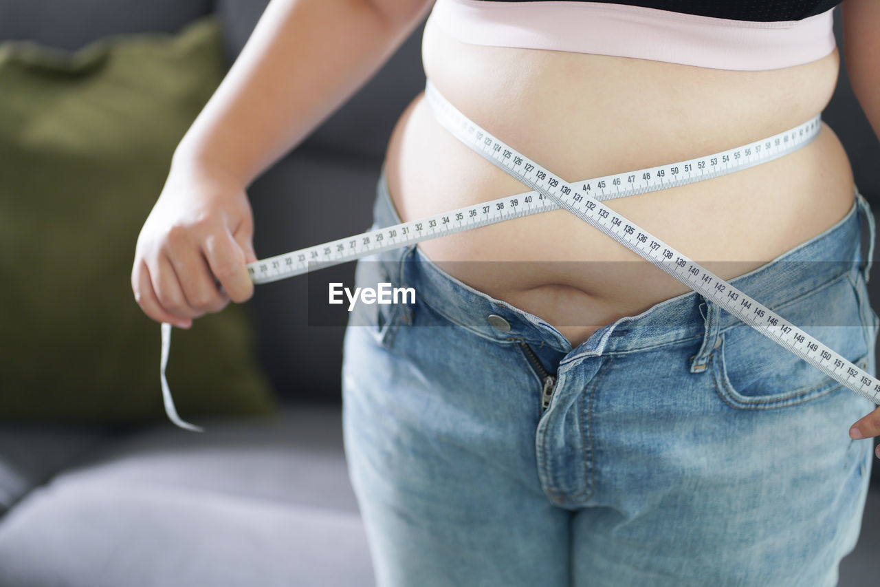 midsection of woman holding tape measure
