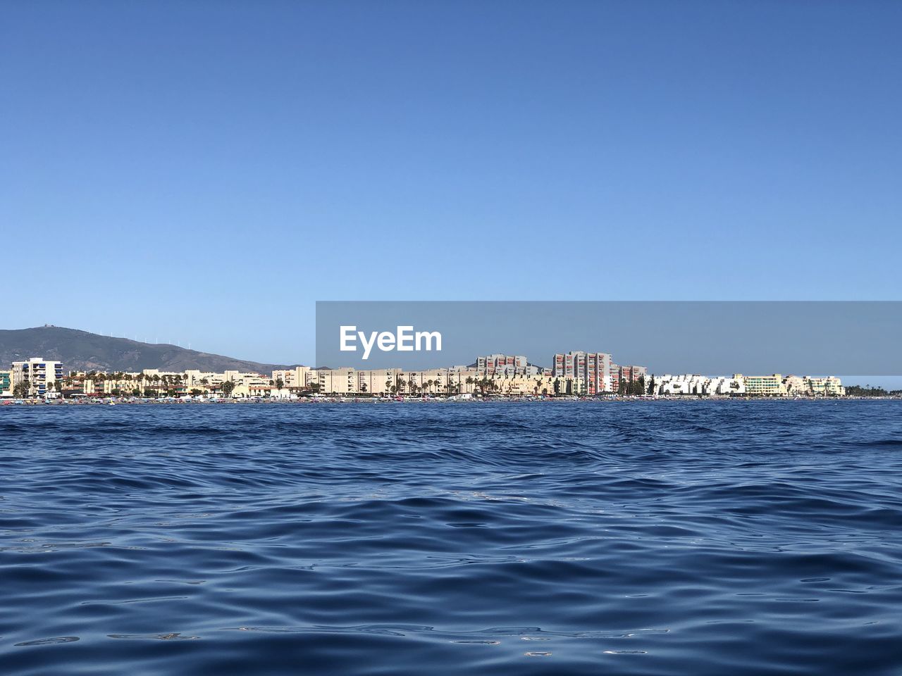 SCENIC VIEW OF SEA AND BUILDINGS AGAINST CLEAR SKY