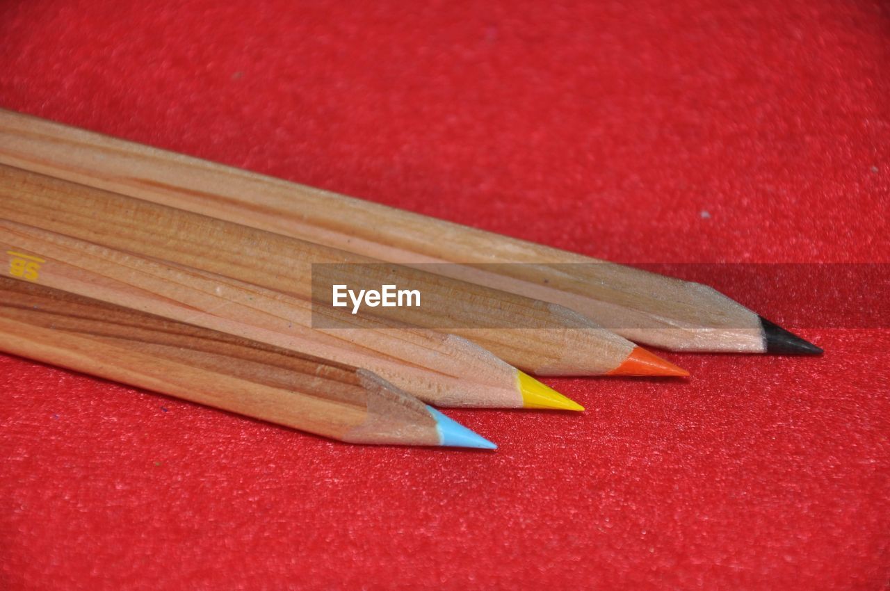 pencil, red, writing instrument, no people, still life, colored pencil, close-up, sharp, indoors, wood, education, wing, high angle view, creativity, table, craft, studio shot