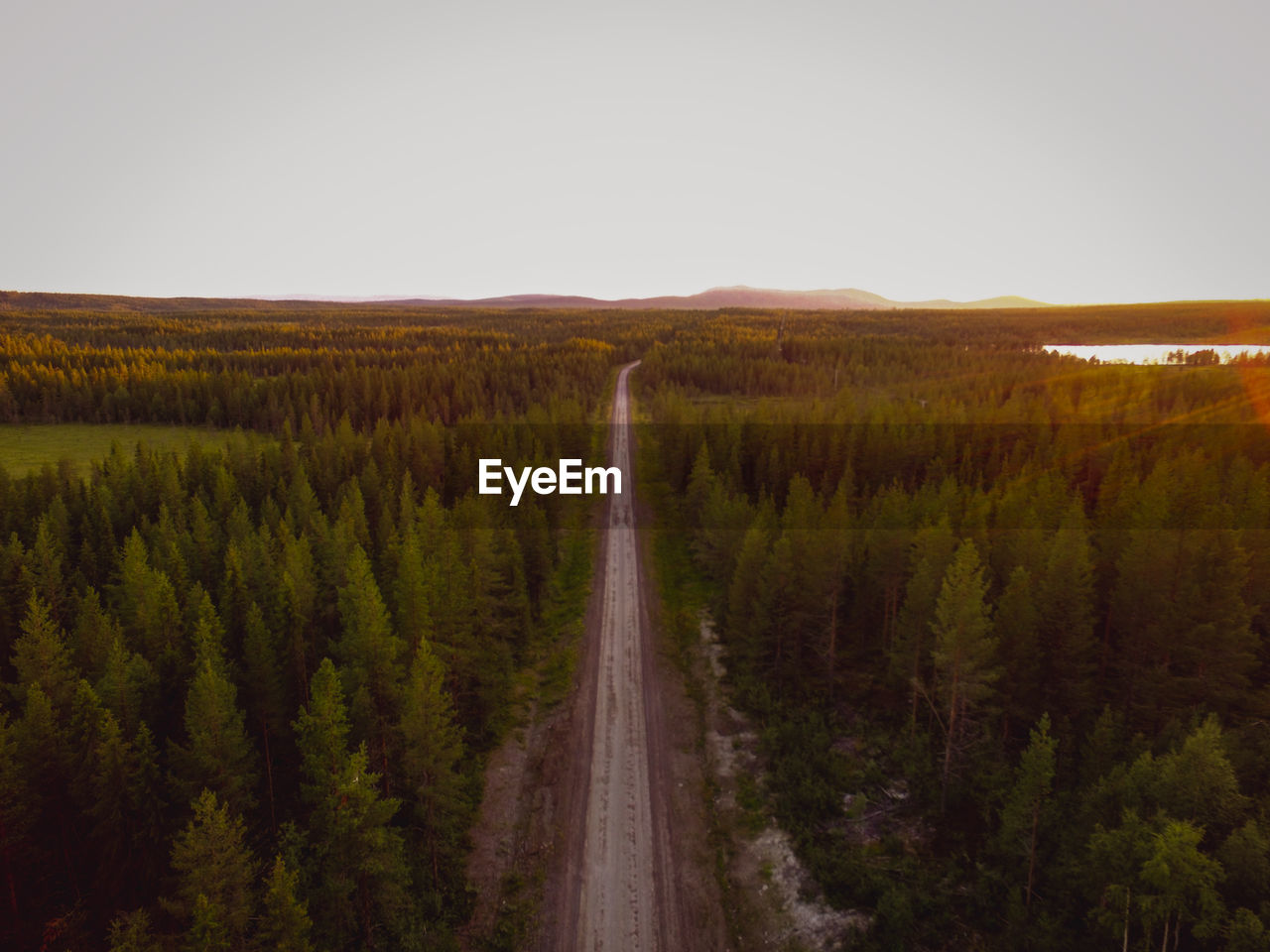 Aerial view of road amidst trees against clear sky during sunset