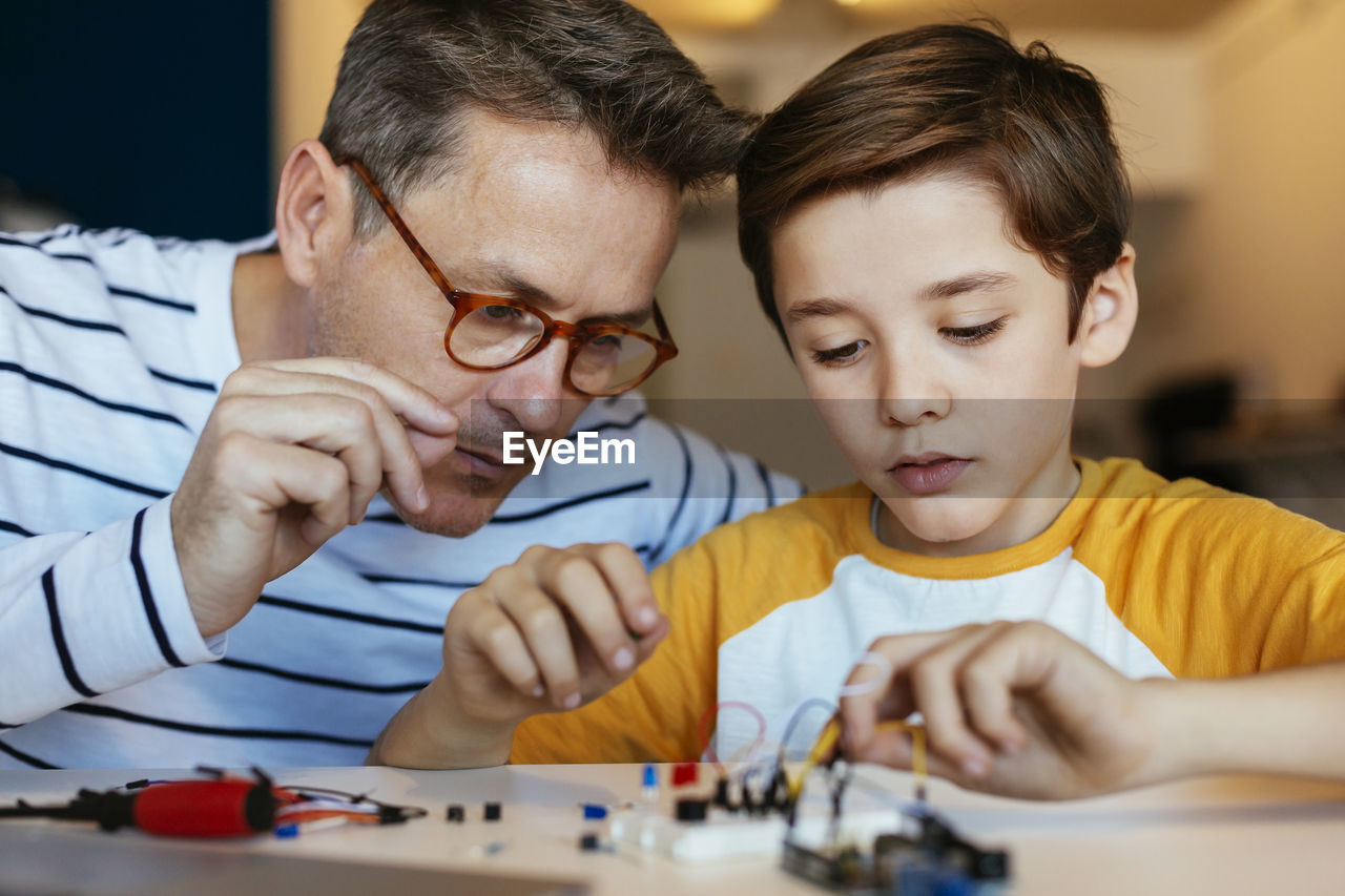 Father and son assembling an electronic construction kit