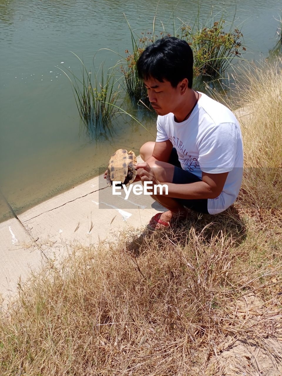 FULL LENGTH OF BOY SITTING ON LAKE