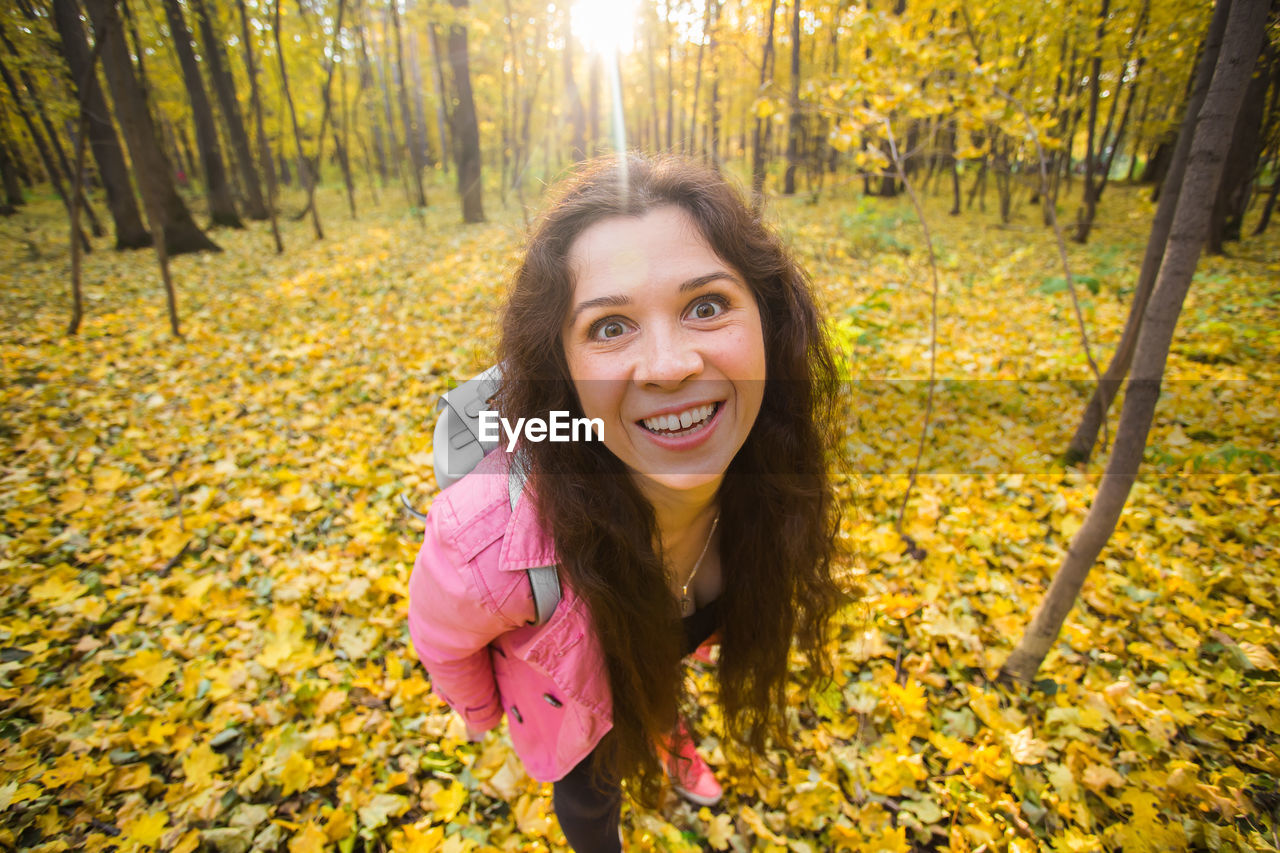 PORTRAIT OF SMILING YOUNG WOMAN IN AUTUMN
