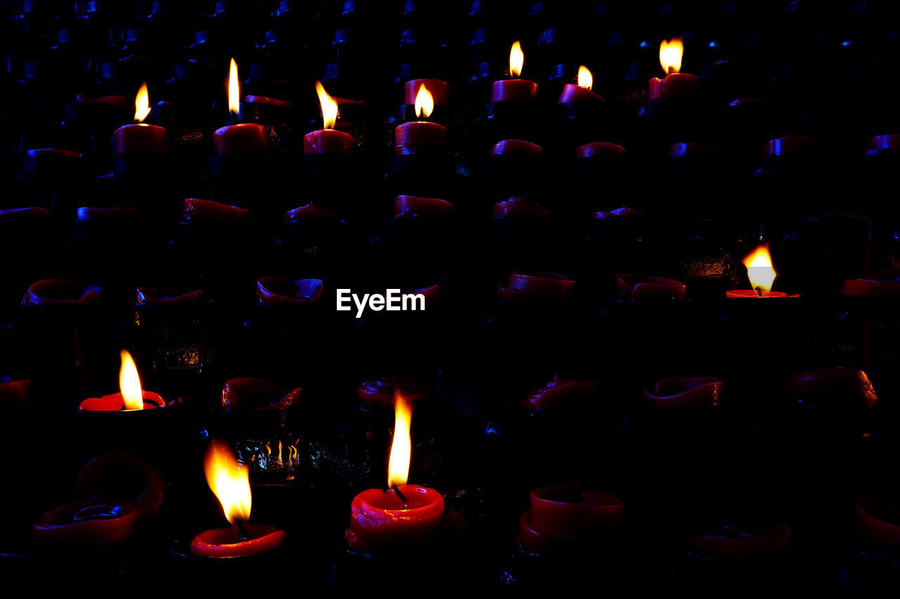 CLOSE-UP OF LIT CANDLES IN DARK ROOM