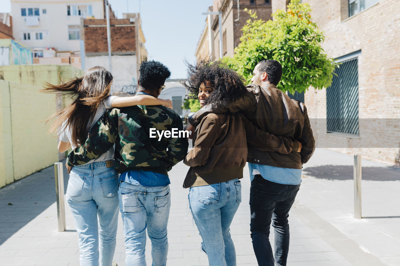 Rear view of stylish friends walking on urban street