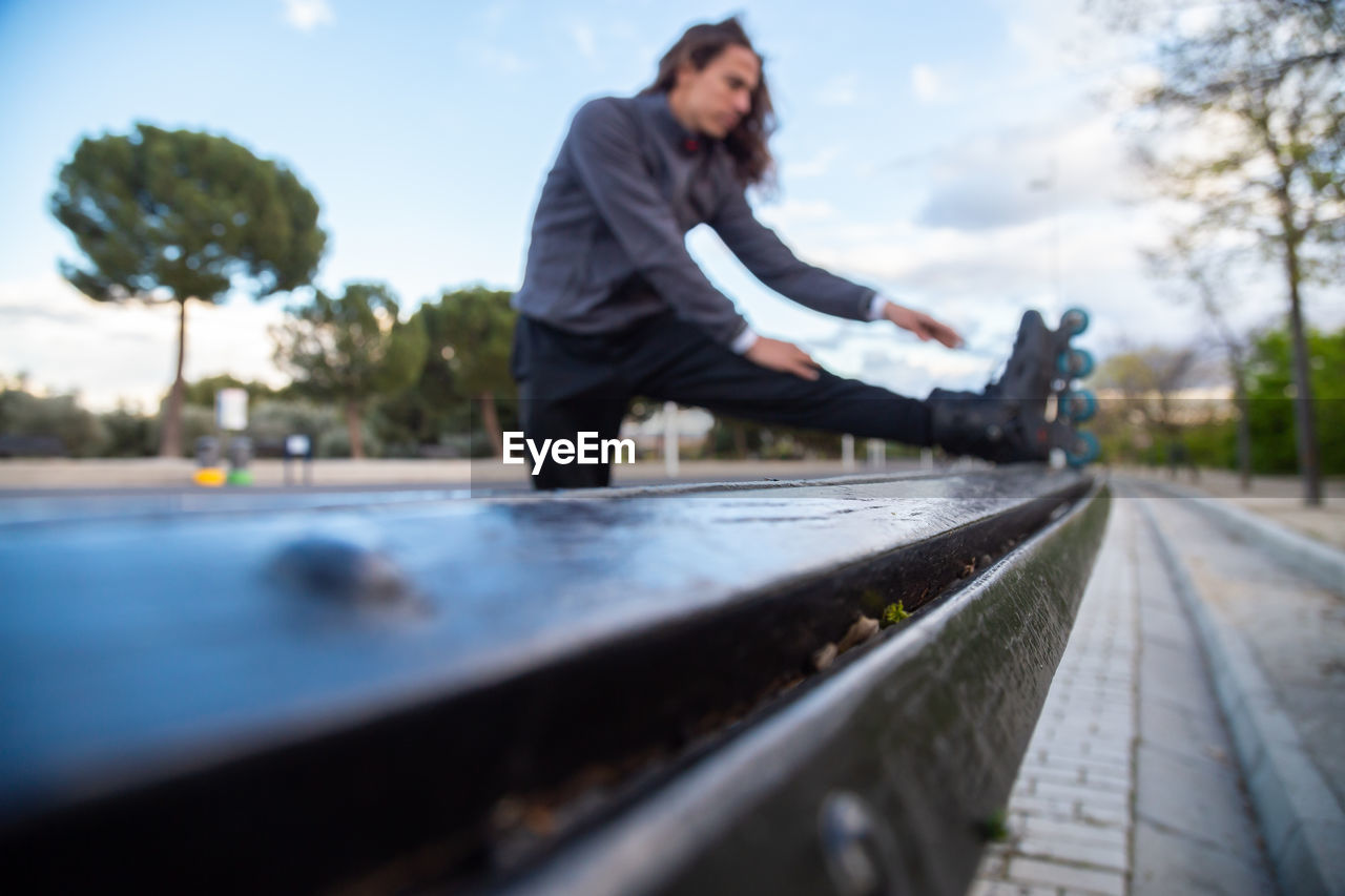 SIDE VIEW OF WOMAN ON RAILROAD TRACK AGAINST SKY