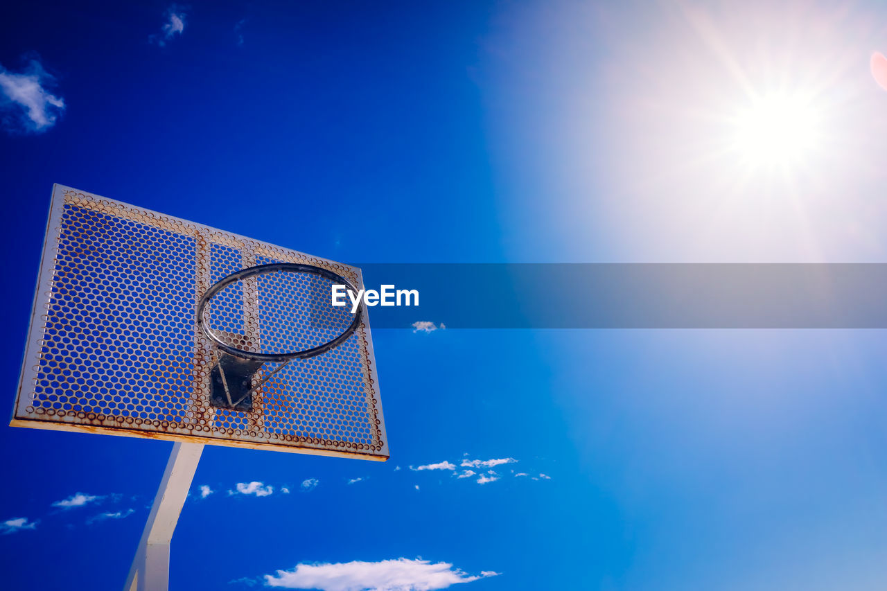 LOW ANGLE VIEW OF BASKETBALL HOOP AGAINST BLUE SKY ON SUNNY DAY