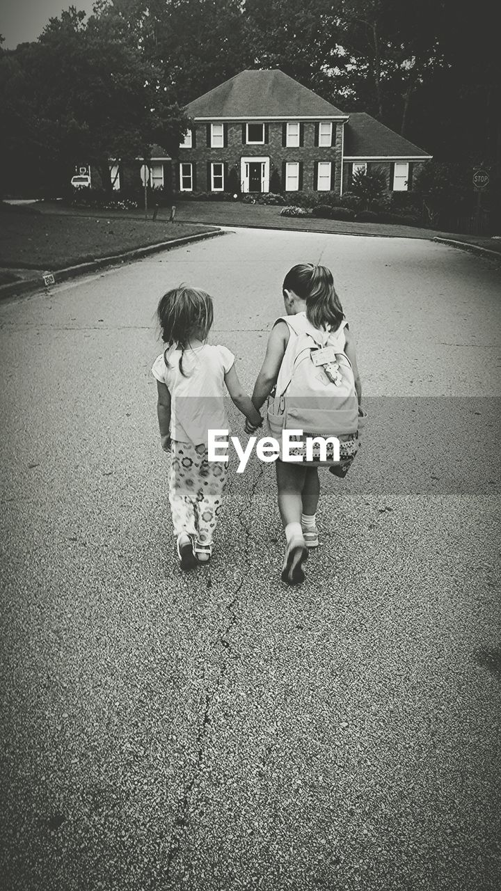 Sisters holding hands on footpath