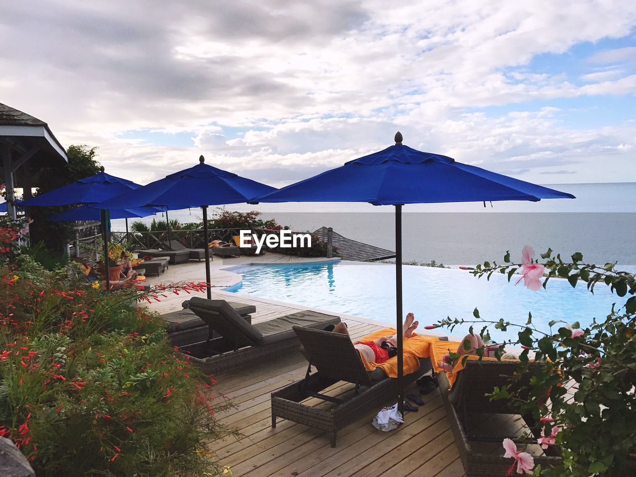 Lounge chairs by swimming pool at beach against sky