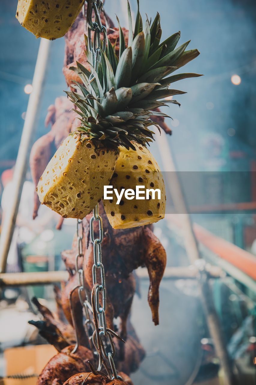 Close-up of fruit and roasted chicken hanging for sale at store