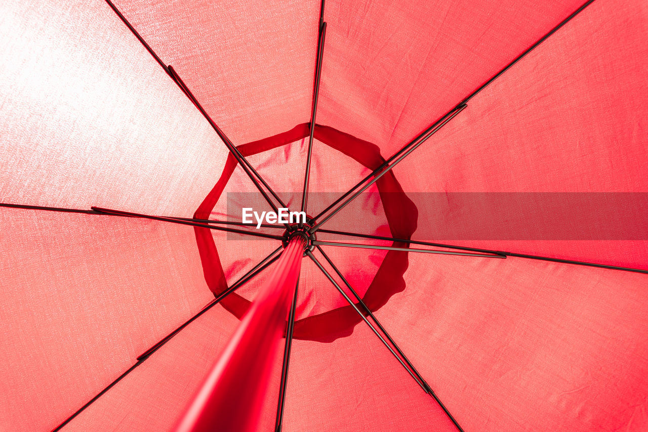 LOW ANGLE VIEW OF UMBRELLA ON PINK ROOF