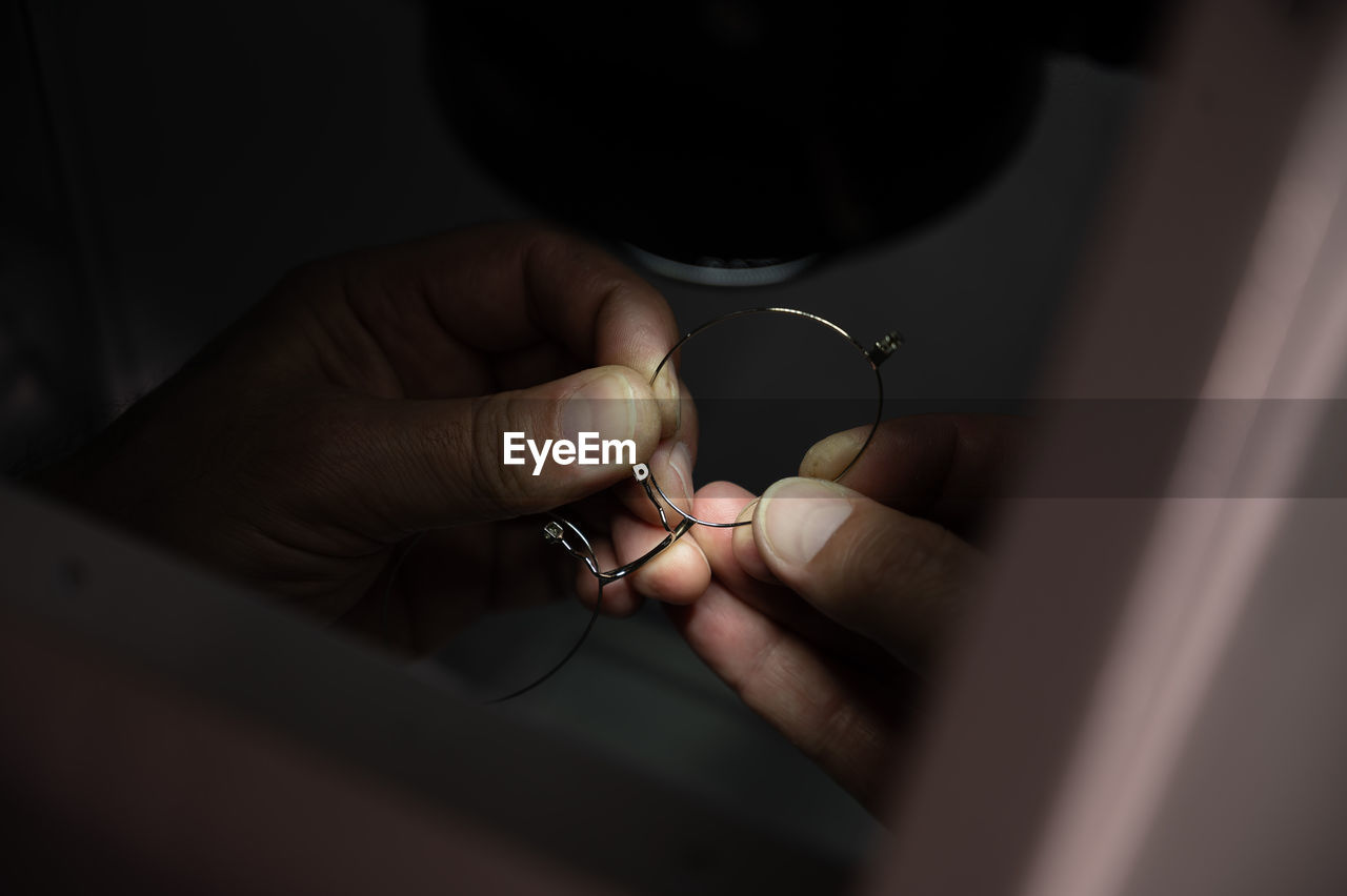 Cropped hand of person holding broken eyeglasses