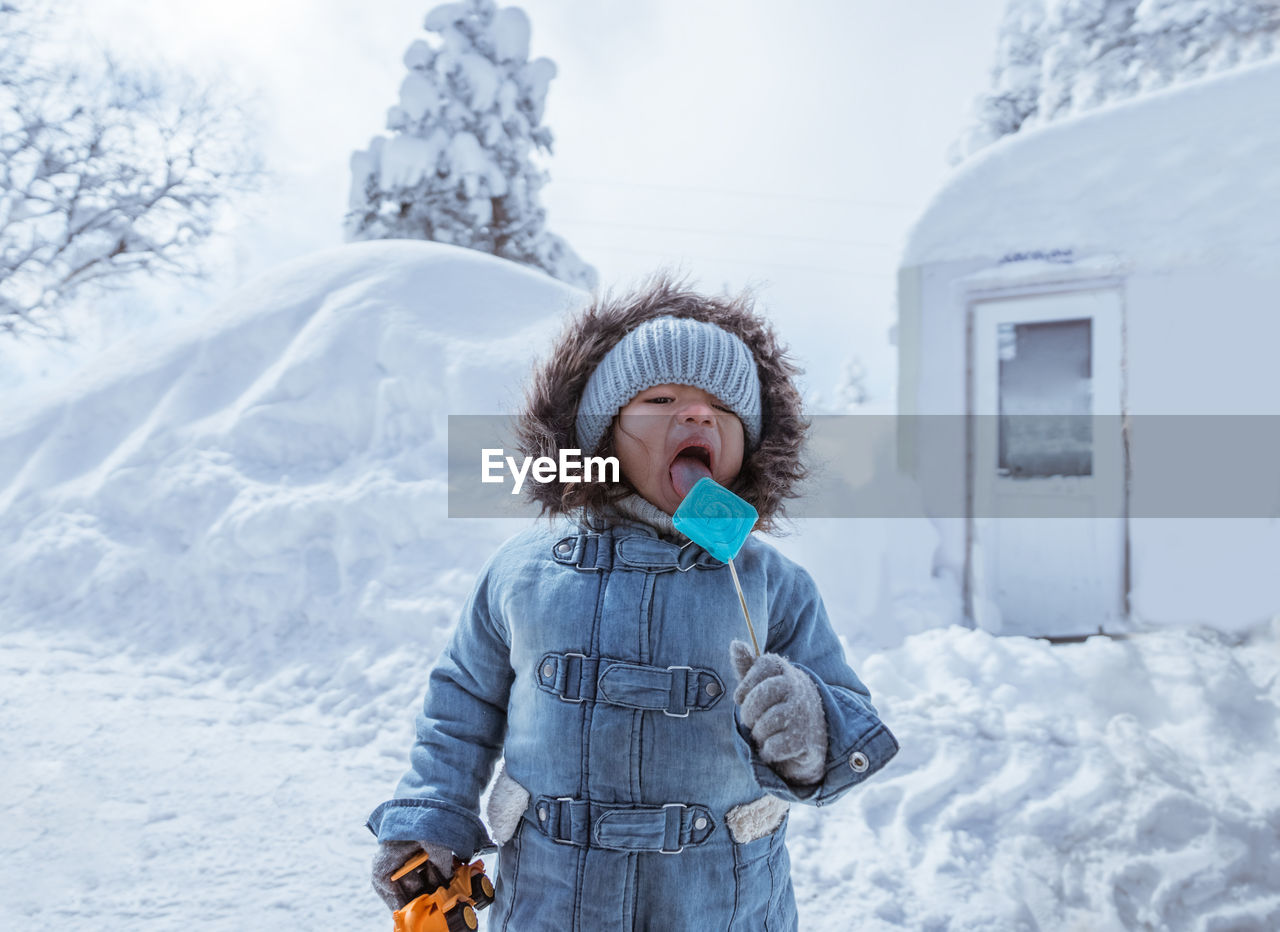 portrait of young woman standing on snow covered landscape