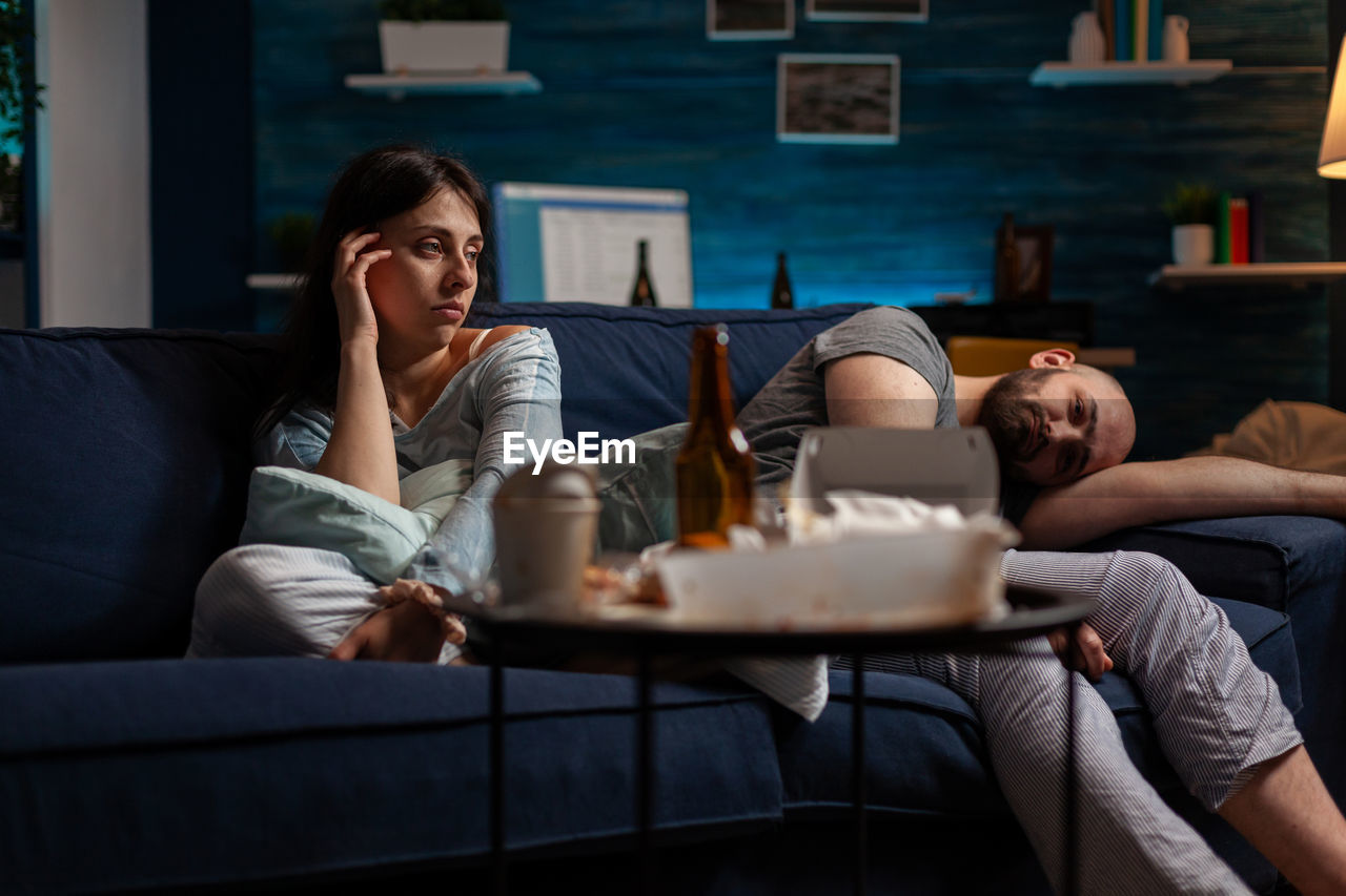 Lazy couple sitting on sofa at home