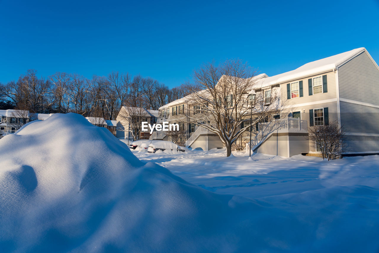 Winter snow covered houses and buildings against clear blue sky in christmas holiday.