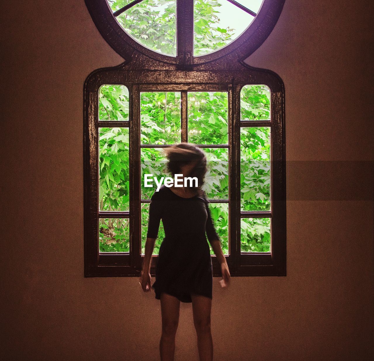 Woman standing by window at home