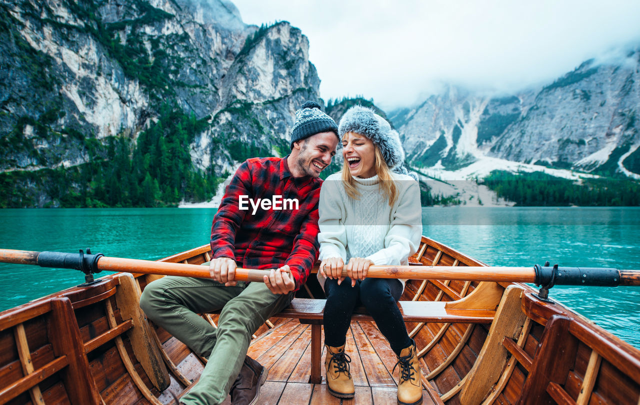 YOUNG COUPLE SITTING ON BOAT AT MOUNTAIN