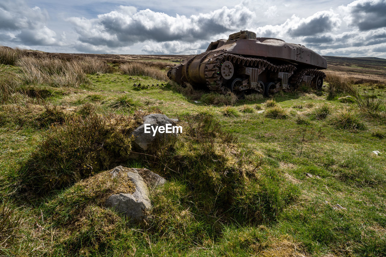 cloud, grass, sky, wilderness, nature, rock, landscape, plant, land, environment, terrain, mountain, tank, no people, scenics - nature, rural area, field, day, history, outdoors, the past, weapon, beauty in nature, non-urban scene, transportation, adventure, geology, architecture, travel, abandoned, remote, green, mode of transportation