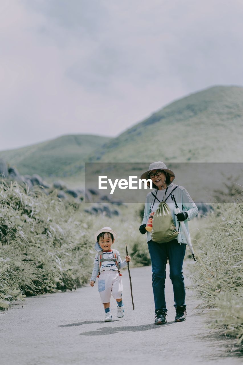 REAR VIEW OF PEOPLE STANDING ON MOUNTAIN