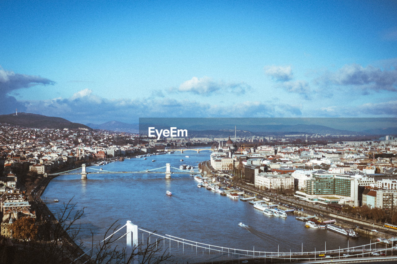 HIGH ANGLE VIEW OF CITY BY SEA AGAINST SKY