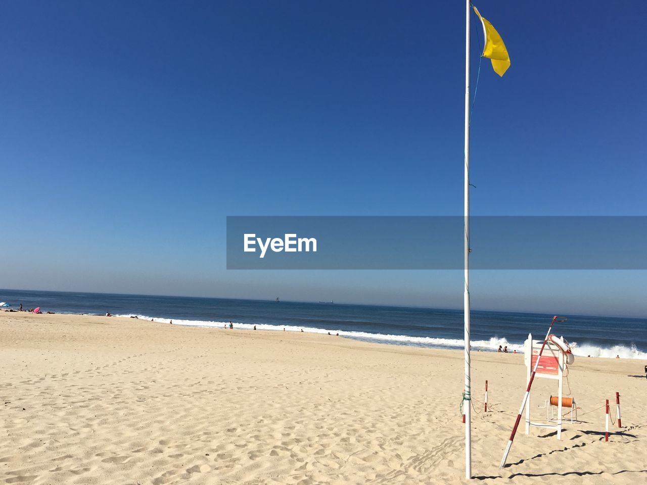Flag on sand at beach against blue sky