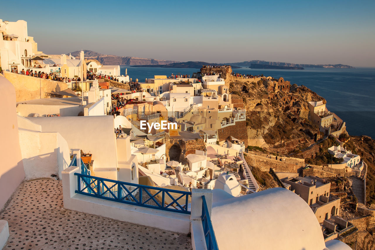 Tourists looking at the amazingly beautiful sunset at la caldera in oia city in santorini island