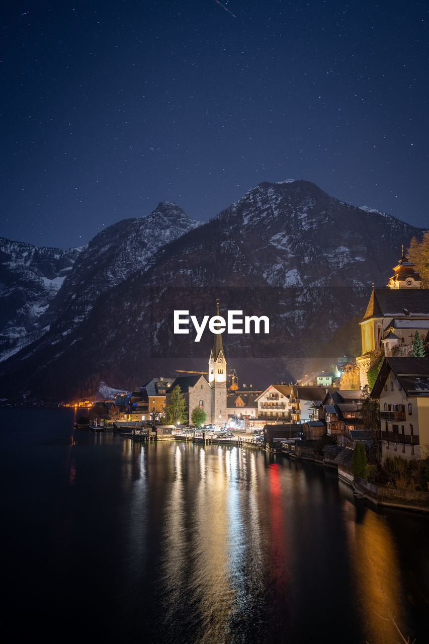 Wonderful cozy town on bank of a lake illuminated during night, vertical, hallstatt, austria, europe