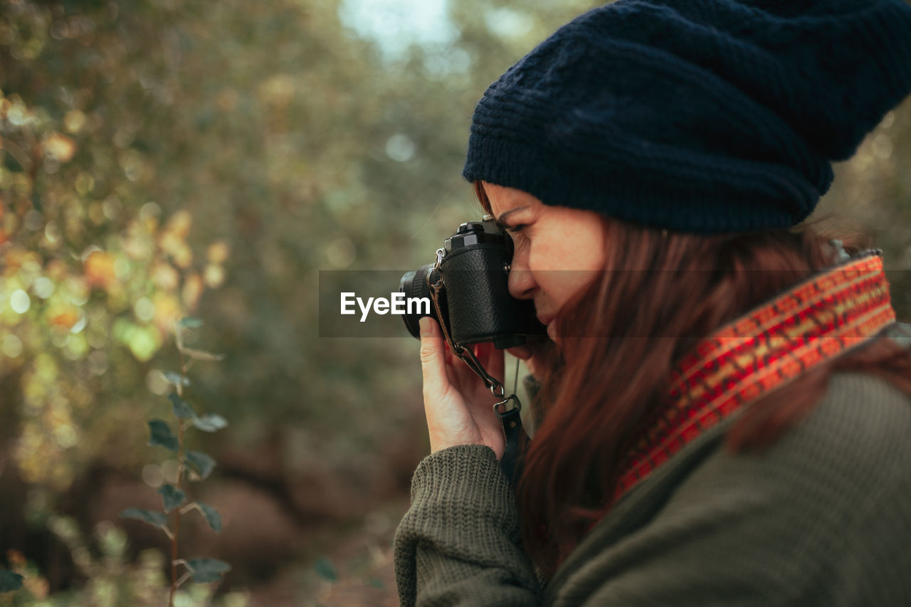 Woman holding camera while standing during winter