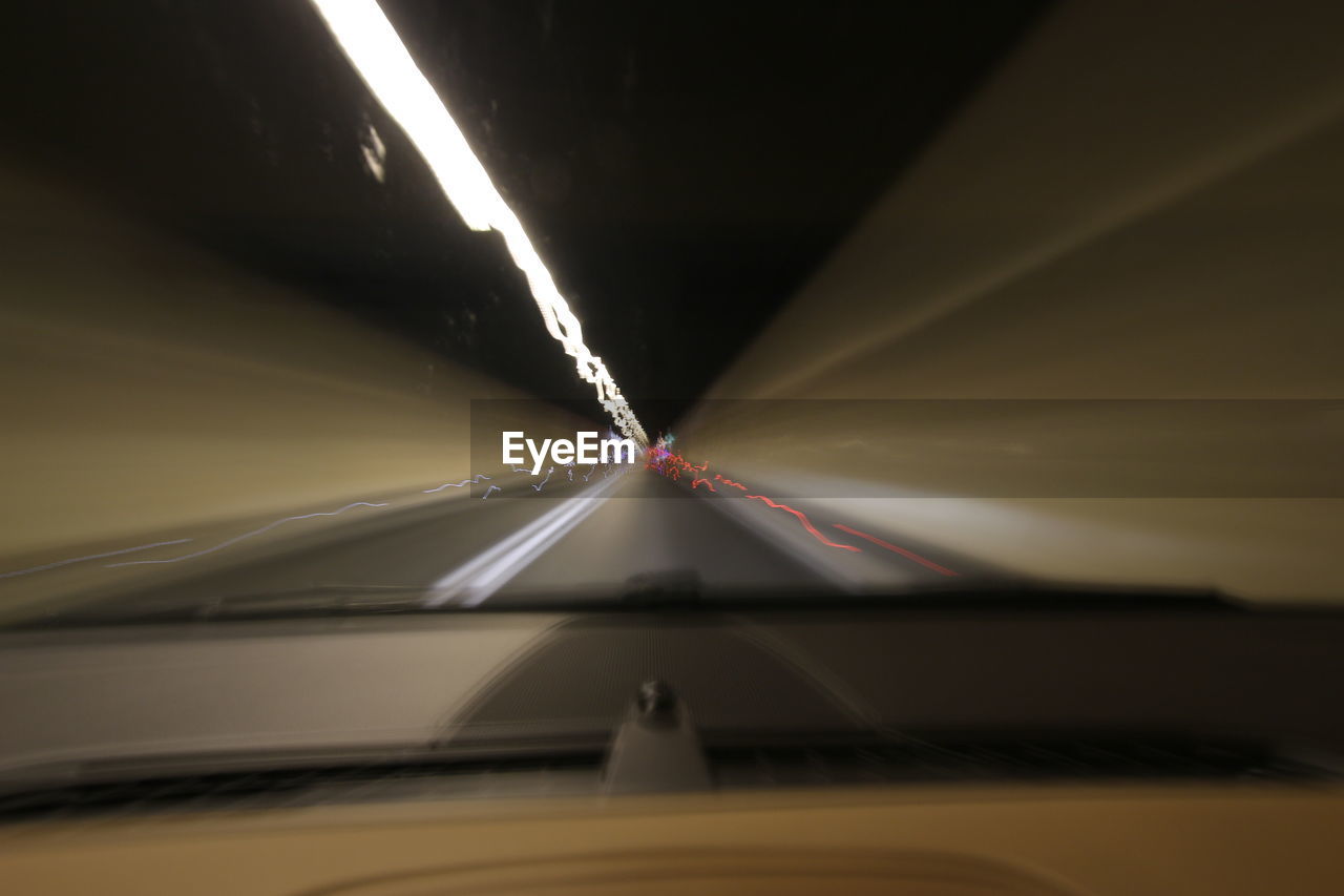 ILLUMINATED LIGHT TRAILS ON ROAD SEEN THROUGH CAR