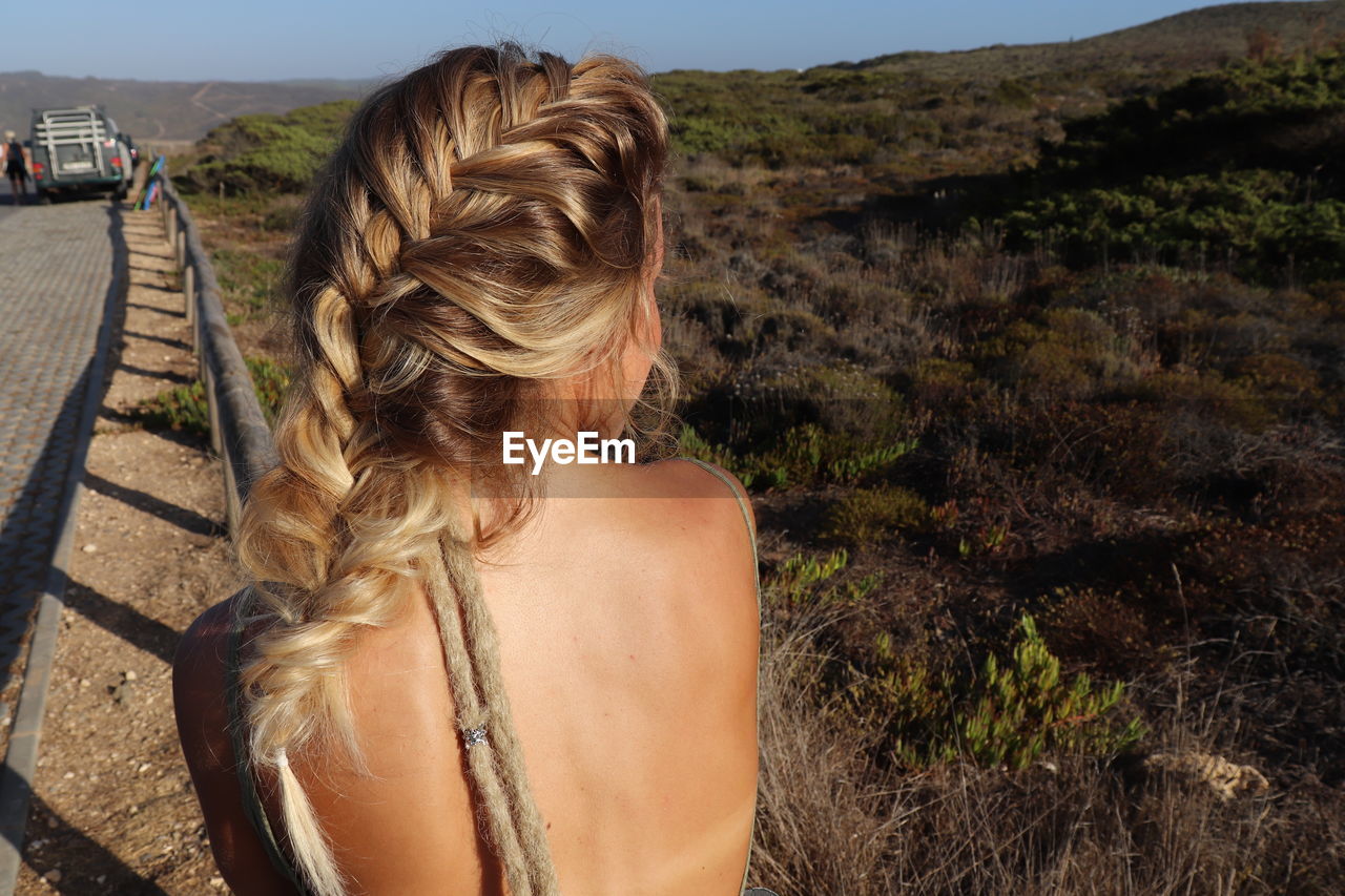 REAR VIEW OF WOMAN STANDING IN A BEAUTIFUL LANDSCAPE