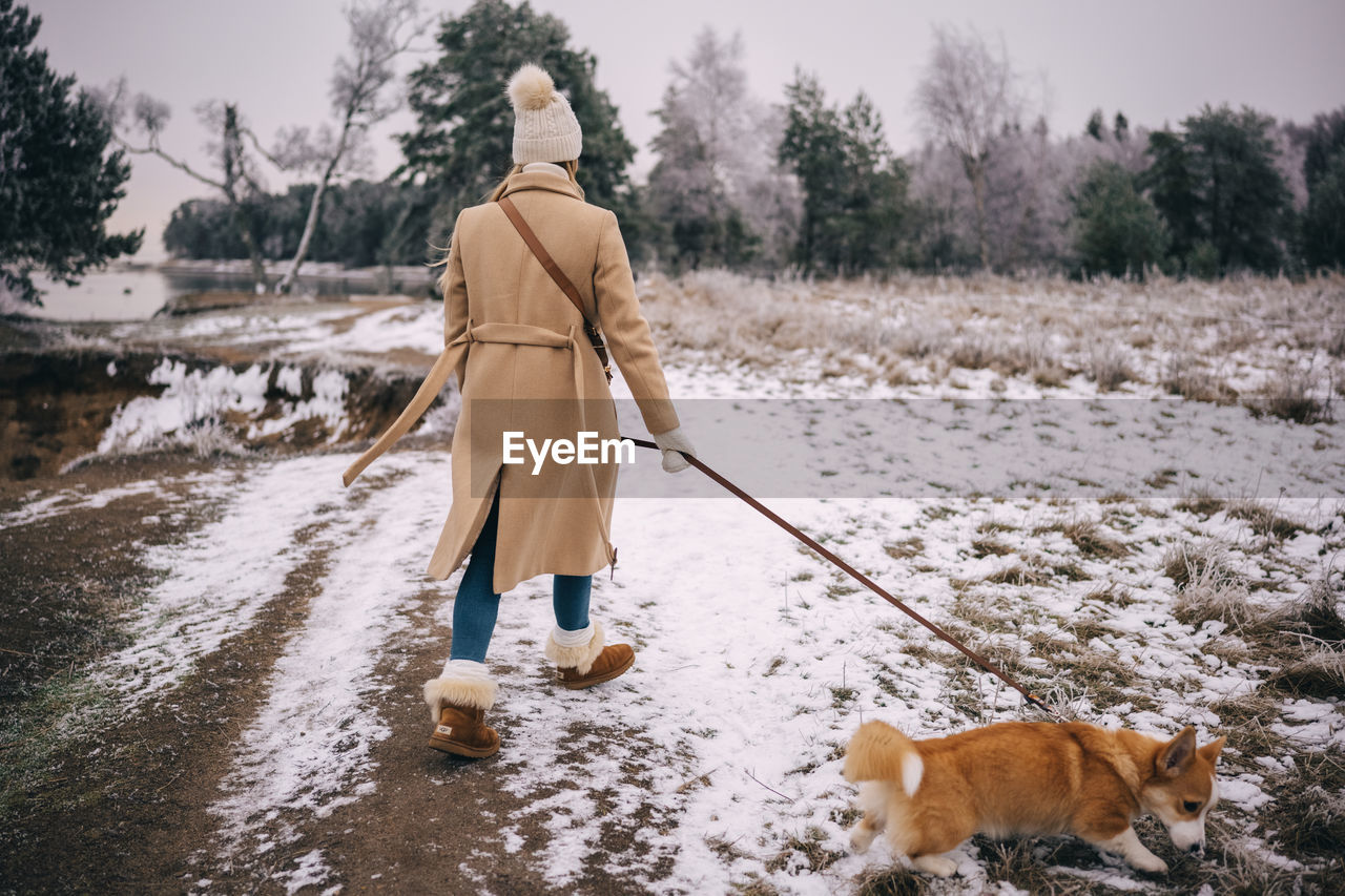 rear view of man walking on snow covered field