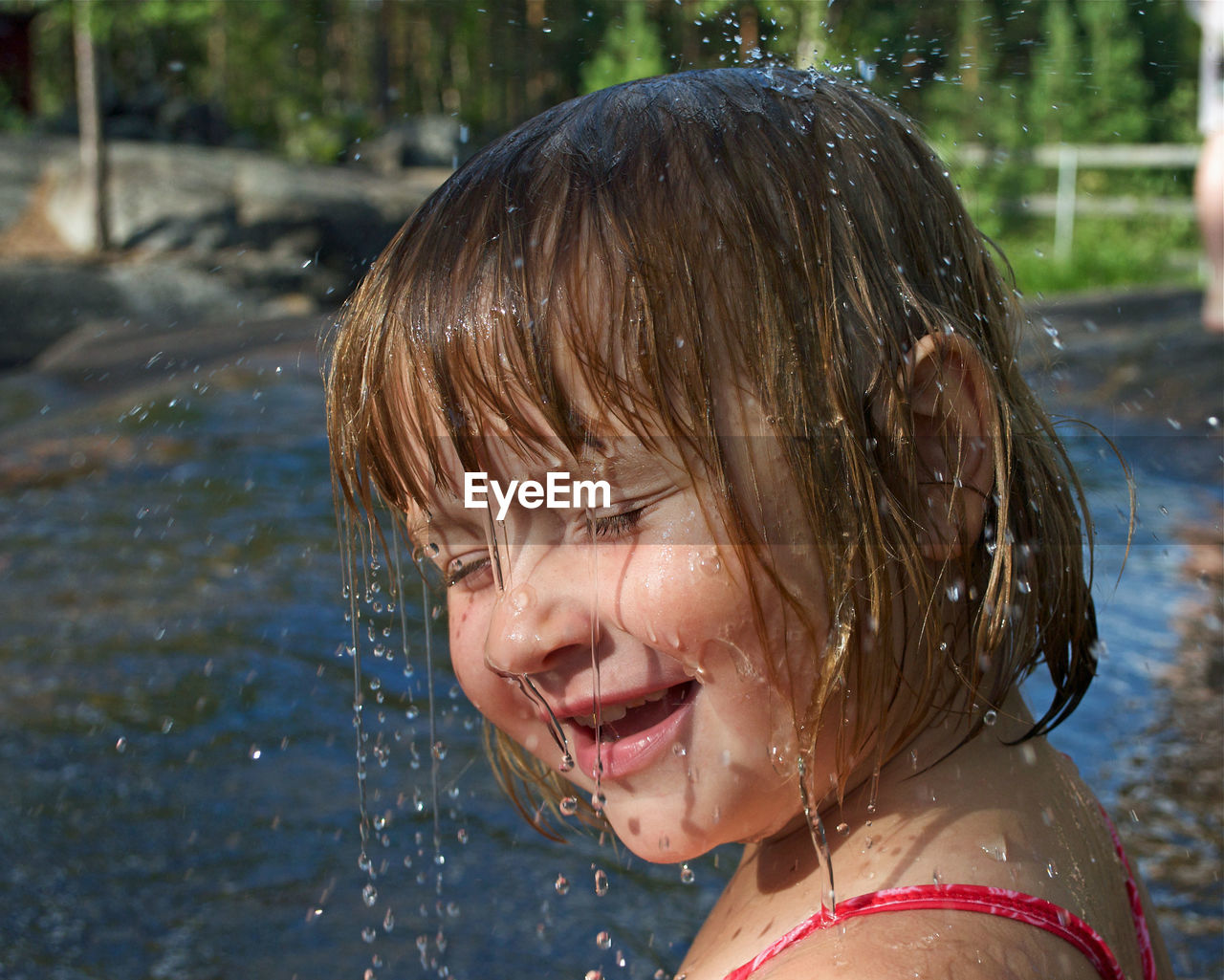 Close-up of water splashing on girl smiling by river