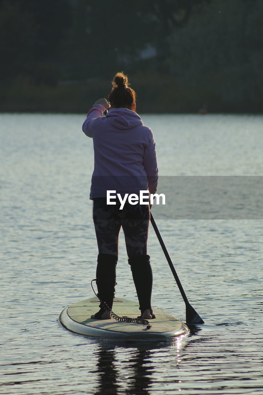 Rear view of woman paddleboarding in lake