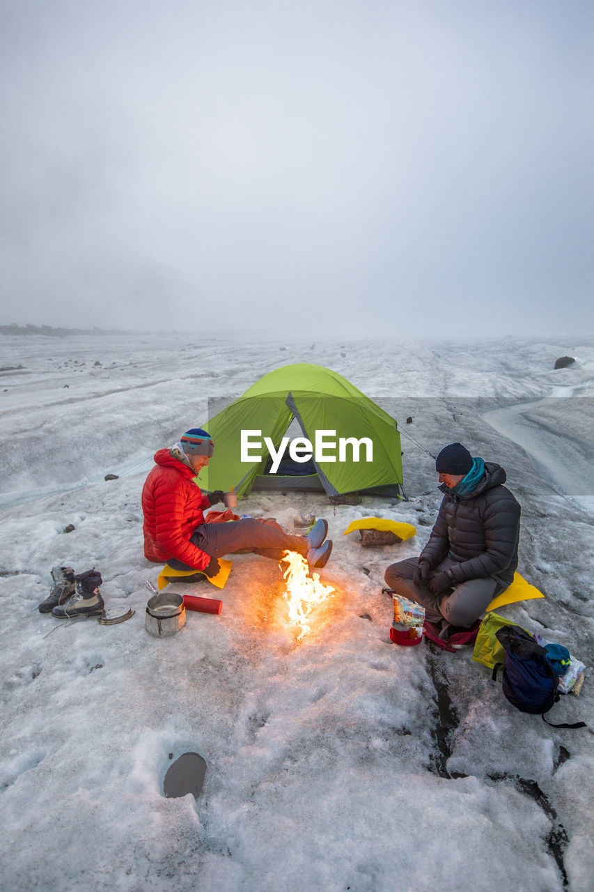 Mountaineers enjoy campfire while camping on a glacier, baffin island